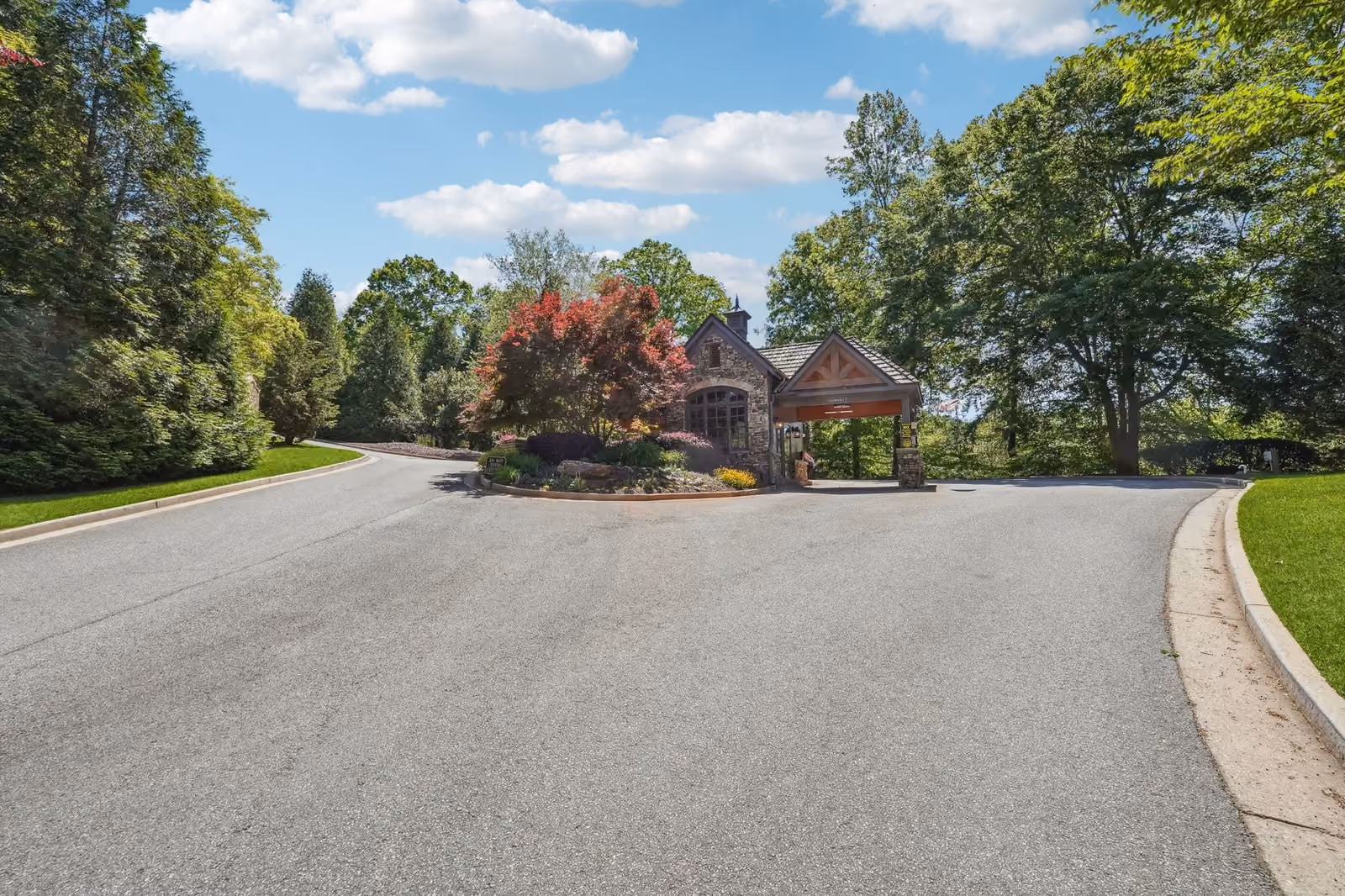 Achasta primary gate , stone gatehouse with timber porte-cochère, ornamental landscaping, wide paved entry sweep off Long Branch Road